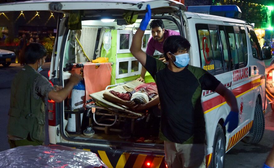 Medical staff load an injured man into an ambulance after two powerful explosions outside the airport in Kabul, Afghanistan, on Thursday.