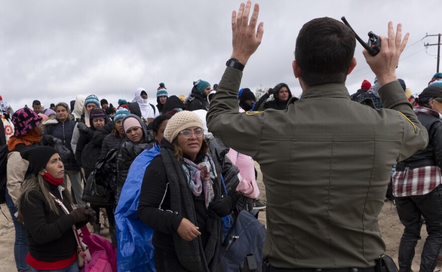 Peruvian Julia Paredes, left in white hat, listens to instructions from a Border Patrol agent with others seeking asylum as they wait to be processed after crossing the border with Mexico nearby, Thursday, April 25, 2024, in Boulevard, Calif. Mexico has begun requiring visas for Peruvians in response to a major influx of migrants from the South American country. The move follows identical ones for Venezuelans, Ecuadorians and Brazilians, effectively eliminating the option of flying to a Mexican city near the U.S. border. (AP Photo/Gregory Bull)