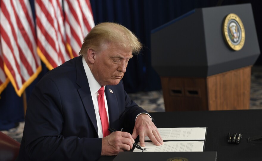 President Trump signs one of four executive orders addressing the economic fallout from the pandemic in Bedminster, N.J., on Aug. 8. The Trump administration has given employers the option to stop collecting payroll taxes, but workers may have to repay the money next year.