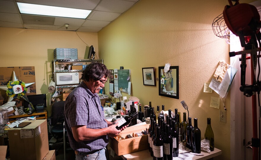 Winemaker Gustavo Brambila hand-labels a wine bottle.