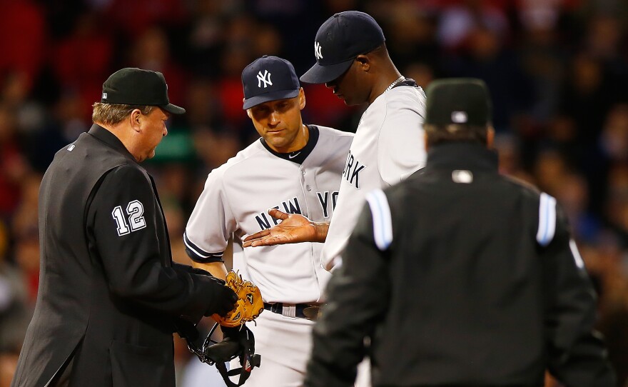 Home plate umpire Gerry Davis checks out the hand of Michael Pineda of the New York Yankees in front of teammate Derek Jeter before throwing him out of the game in the second inning against the Boston Red Sox.