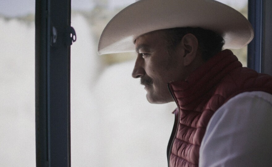 Humberto Navarro, National Water Commission, Guanjuato, Mexico. A close-up side view of a Mexican man wearing a cowboy hat and red vest.