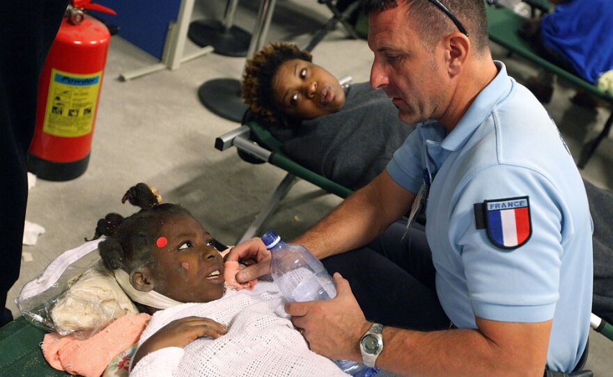 An injured girl is given water by a French aid worker at a makeshift field hospital in Port-au-Prince, Haiti, on Wednesday. Governments and aid agencies launched a massive relief operation after a powerful earthquake rocked the nation.