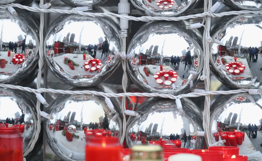 Candles left by mourners are reflected in Christmas balls on Tuesday, near the crime scene where a truck plowed into a crowded Christmas market on Monday. At least a dozen people are dead, and nearly 50 injured