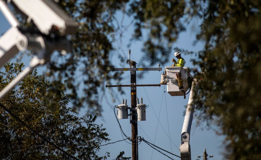 A PG&E contractor works on utility poles along Highway 128 near Geyserville, Calif., on October 31, 2019. The utility is shutting off power for hundreds of thousands in an effort to not spark wildfires.