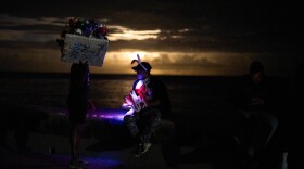 Street vendors chat on the Malecón during a blackout in Havana, Monday, March 16, 2026.