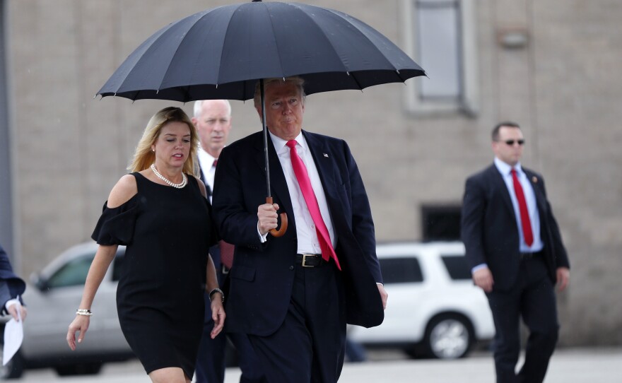 Republican nominee Donald Trump holds an umbrella while walking in the rain with Florida Attorney General Pam Bondi, as they arrive at a campaign rally in Tampa, Fla., in August.
