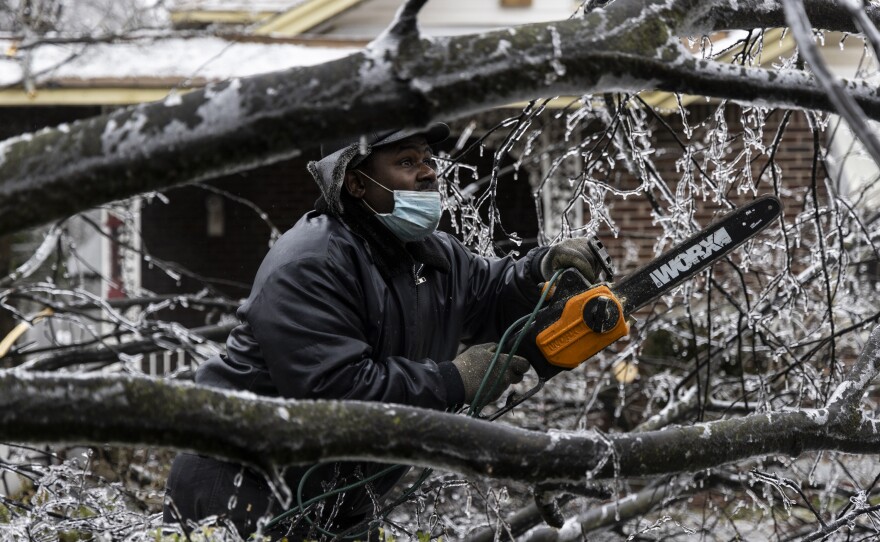 Edward Caldwell works to clear a downed tree at his mother's house on Thursday in Memphis, Tenn.