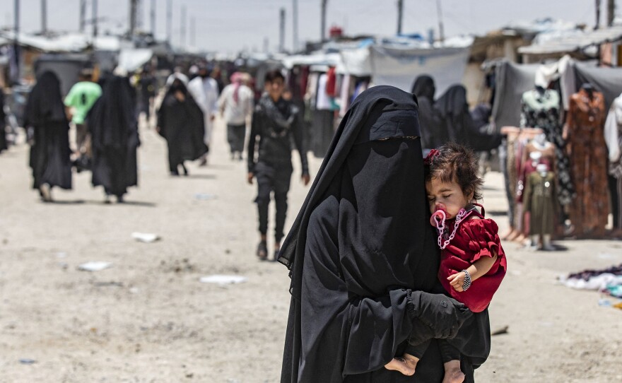 A woman carries a child as she walks through the al-Hol refugee camp in northeastern Syria in October 2023.