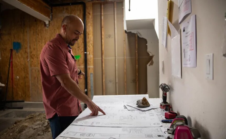 Adam Hardesty looks through floor plans at his home in Carlsbad on Feb. 19, 2025. Hardesty is currently converting the garage of his three-story condo into a ground-floor apartment, despite opposition from his own Homeowners Association.