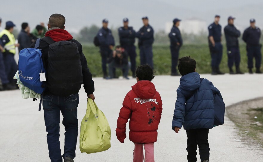 A migrant and children carry their belongings at the Idomeni camp on Tuesday. In an operation that began shortly after sunrise, hundreds of Greek police began evacuating the sprawling camp.