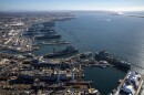 An aerial photo of General Dynamics NASSCO shipyard and Naval Base San Diego with several ships aligned at piers and in docks.