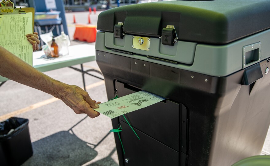 A federal appeals court is allowing Texas Gov. Greg Abbott's limit of one absentee ballot drop-off spot per county to stand, saying voters have many options. Here, a worker puts a ballot into a lock box at a drive-through mail ballot hand delivery center in Austin.