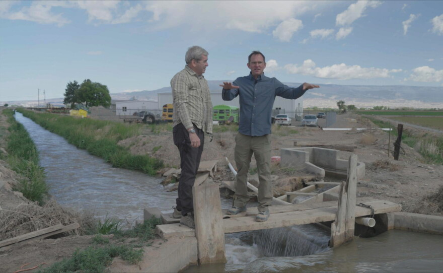 RESOLVE TO SOLVE Host Miles O'Brien and farmer Reid Fishering walk the plank over the irrigation ditch, which is the lifeline for his sweet corn farm. (Delta, CO)