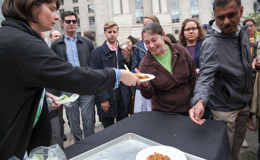 A volunteer hands out plates of paella.