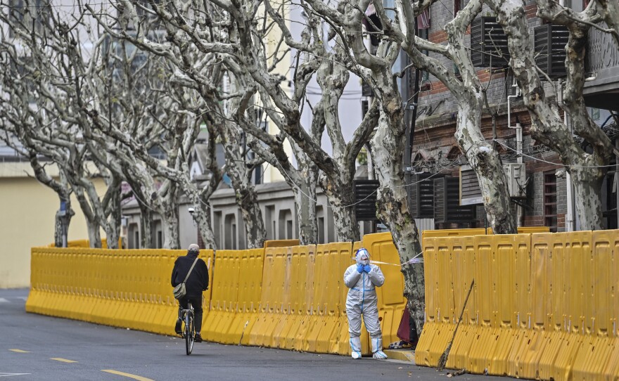A worker in protective gear stands by barriers set up as part of lockdown measures against COVID-19 in Jing'an district, in Shanghai on March 31.