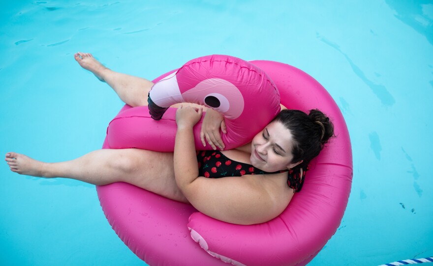 Anna Helmig, 26, hugs an inflatable flamingo in the pool at Camp Roundup.