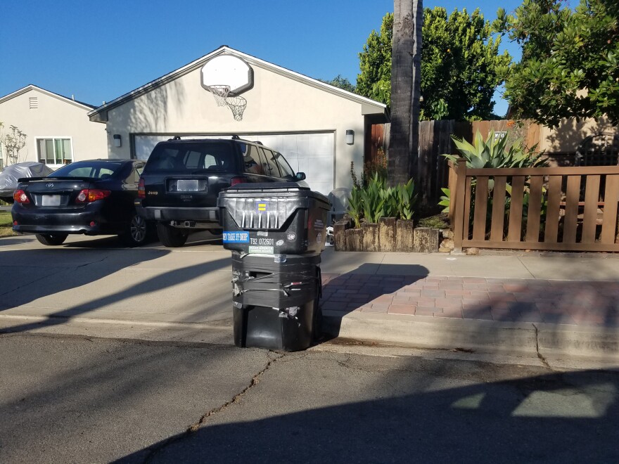 A damaged city of San Diego trash bin sits in front of a house in September, 2019.