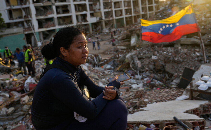 Estefany Landaez sits amid the rubble of a collapsed building in La Guaira, Venezuela, on July 12, 2026, as she waits for news about her two children following the earthquakes.