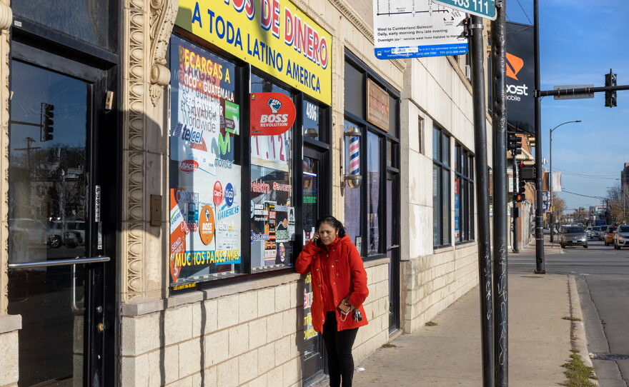 Nelly Villanueva calls her mother in Mexico outside a money order business in Chicago in 2021.