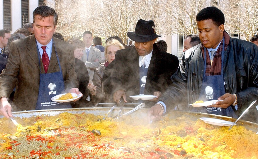 Former Gov. Jeb Bush (left) serves helpings of paella to guests attending the Miami-Dade Day festivities in 2002 with with Florida state Rep. Gary Siplin (center) and Sen. Kendrick Meek.