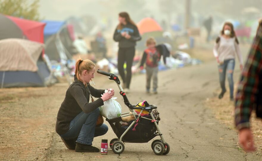 An evacuee tends to her baby Thursday at an encampment set up in a Walmart parking lot in Chico, Calif.