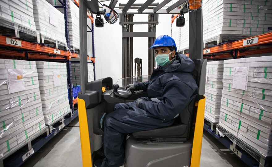 A worker surrounded by boxes of vaccines in the cold storage unit of the Serum Institute of India. In addition to manufacturing the AstraZeneca coronavirus vaccine, the institute produces vaccines for measles, tetanus and many other diseases.