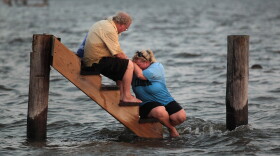 Billy Stinson (L) comforts his daughter Erin Stinson as they sit on the steps where their cottage once stood August 28, 2011 in Nags Head, North Carolina. 
