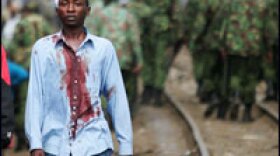 A member of the Kikuyu tribe living in the Kibera slum of Nairobi walks away from Kenyan police during ethnic clashes on Tuesday. The killing of an opposition lawmaker added new fuel to the violence following last month's disputed election.