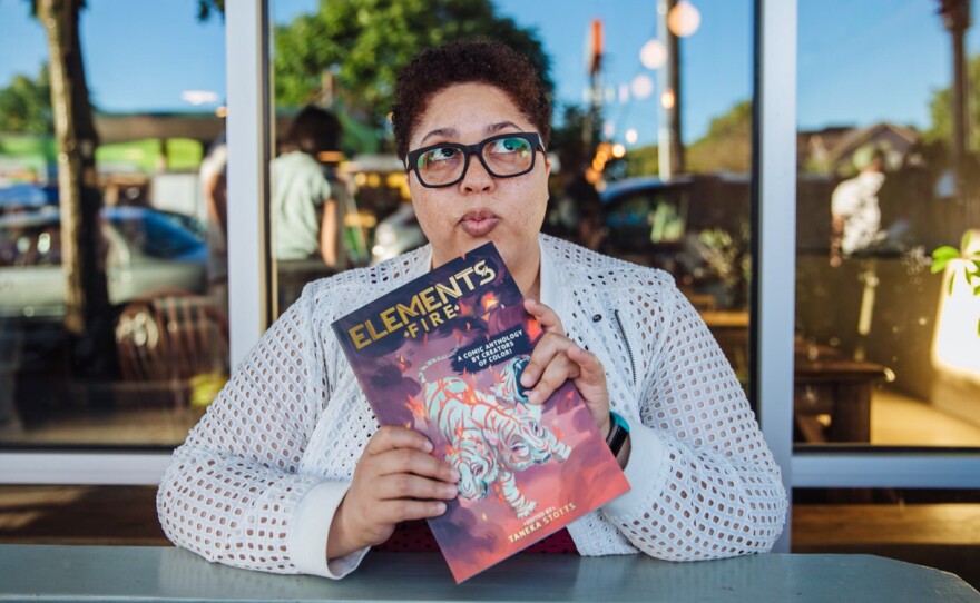 Creator Taneka Stotts holds a copy of her Eisner Award-winning anthology <em>Elements: Fire</em>.