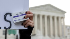 An abortion-rights activist holds a box of mifepristone pills as demonstrators from both anti-abortion and abortion-rights groups rally outside the Supreme Court on March 26, 2024.