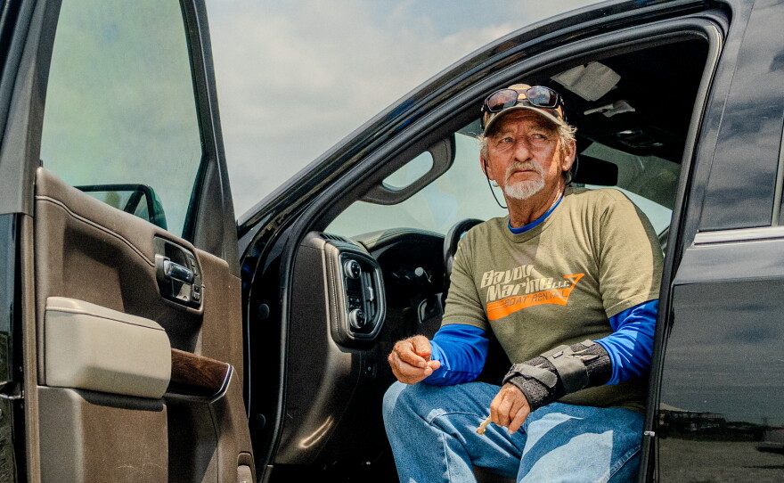 Acy Cooper eats lunch out of his pickup truck at the Myrtle Grove Marina in Port Sulphur, La. on Friday, May 15, 2026. Cooper had just returned to the marina after a shift ferrying oil rig workers from offshore platforms — a job he's taken because of falling shrimp prices and increasing fuel costs.