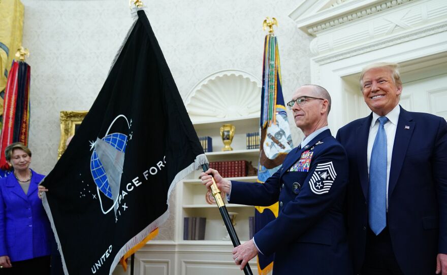 U.S. Space Force senior enlisted adviser Chief Master Sgt. Roger Towberman presents the Space Force Flag to President Trump on Friday in the Oval Office.