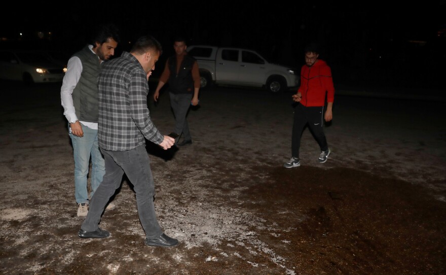 People inspect the area where one of the fired rockets was hit at Bahtiyari neighborhood on Monday in Erbil, Iraq.