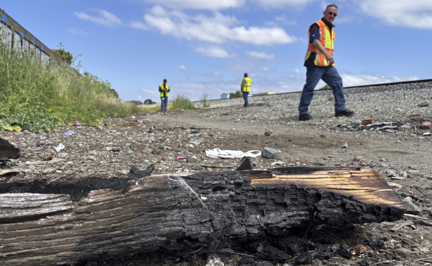 AT&T crew members walk by a "burn pit" near a site where cables were cut.