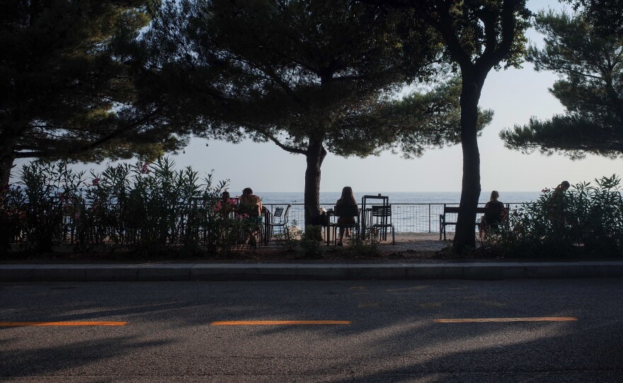 Built in the 1930s, a series of semicircular terraces lines the coast of Trieste where people enjoy the sea.