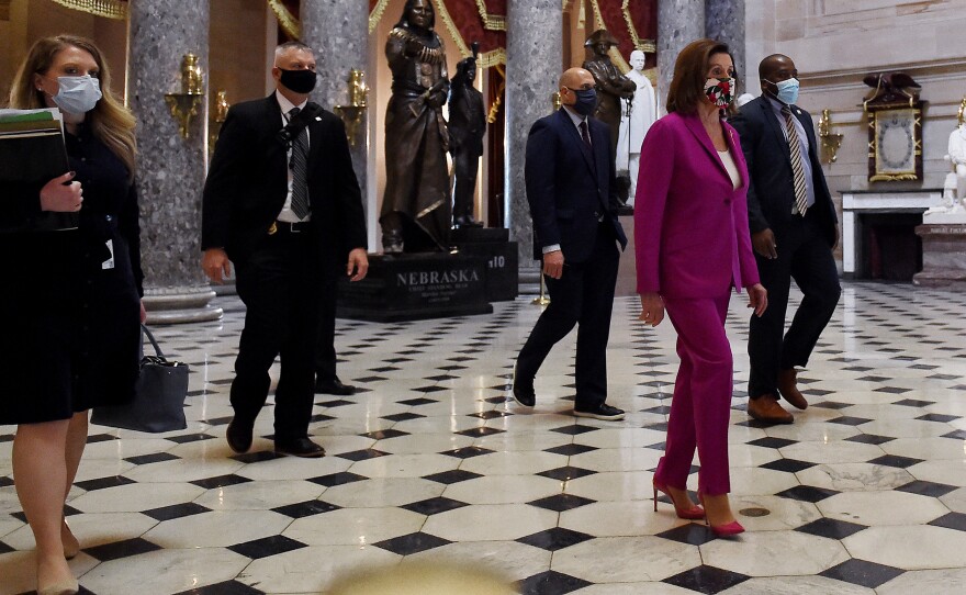 House Speaker Nancy Pelosi, D-Calif., walks past the Statuary Hall ahead of floor debate on a record $3 trillion coronavirus response package Friday to fund the fight against the pandemic and provide emergency payments to millions of Americans.