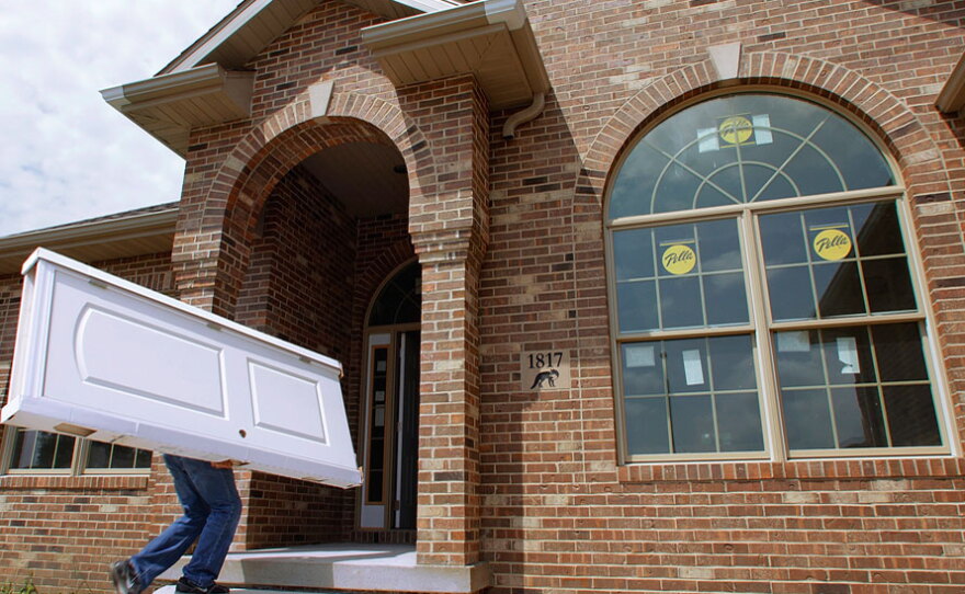 Construction worker Brian Stocks delivers doors July 15 to a  new  home under construction in Springfield, Ill. Homebuilder confidence dropped for the third straight month in August as the struggling economy and a flood of cheap foreclosed properties kept people from buying  new  homes.