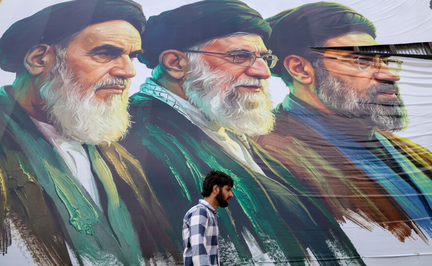 A man walks past a billboard featuring the portraits of (right to left) Iran's new Supreme Leader Ayatollah Mojtaba Khamenei, the late Supreme Leader Ayatollah Ali Khamenei, and the late Supreme Leader Ayatollah Ruhollah Khomeini, in Srinagar, Jammu and Kashmir, on June 15.