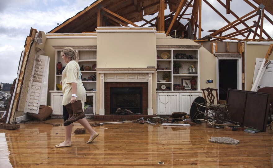 Jenny Bullard carries a pair of boots from her home that was damaged by a tornado in Adel, Ga.