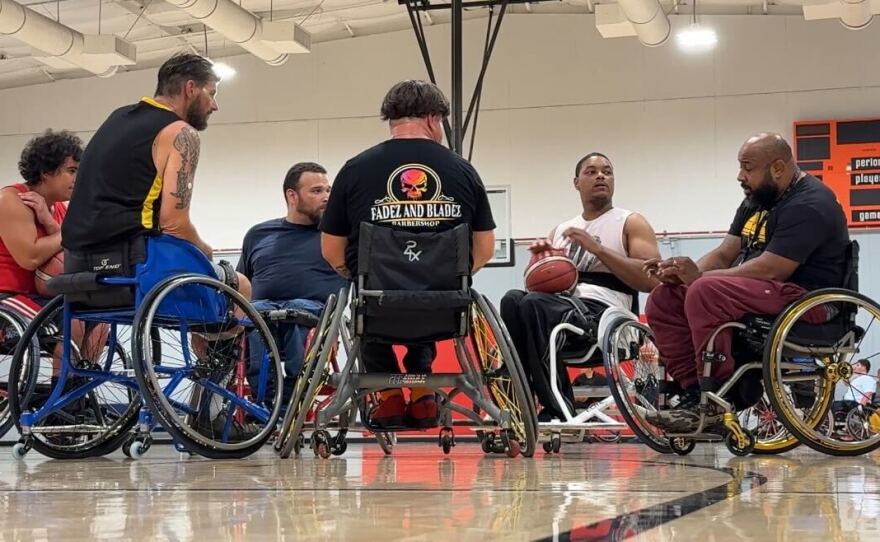 A group of people talk on the court while playing wheelchair basketball in City Heights, Oct. 1, 2025.