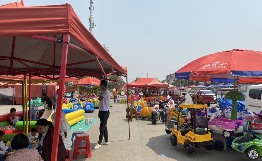 Luo Beiling relocated from a remote village to Qixingguan and now works in this market outside the compound.