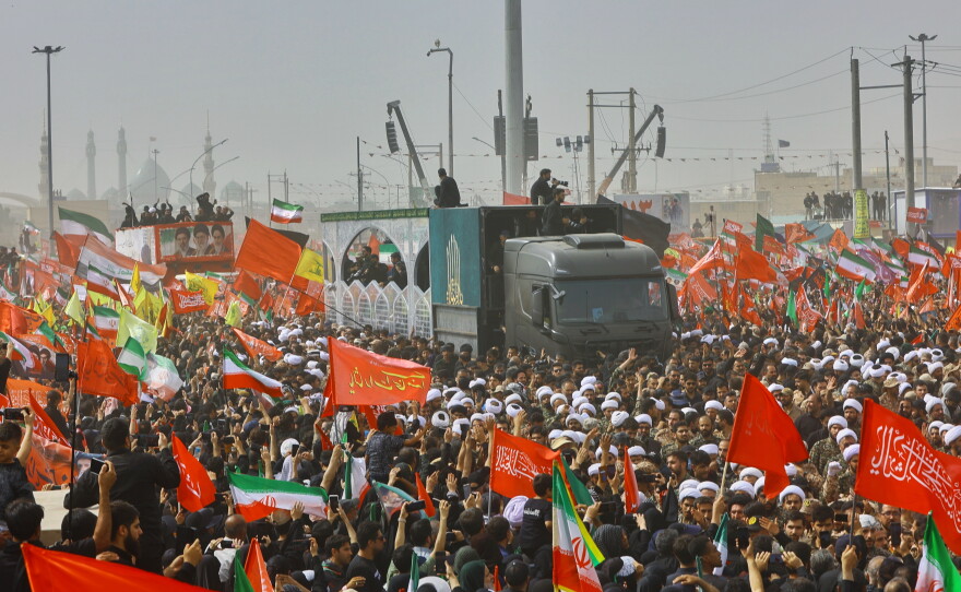 A truck carrying the coffins of the late Iranian Supreme Leader Ayatollah Ali Khamenei and members of his family makes its way through mourners during the funeral procession in Qom, the heart of religious studies in Iran, Tuesday.