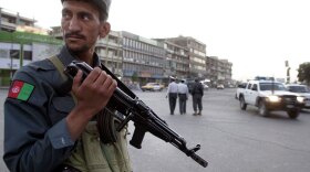 An Afghan policeman stands guard Wednesday in the downtown market area in the capital city of Kabul.