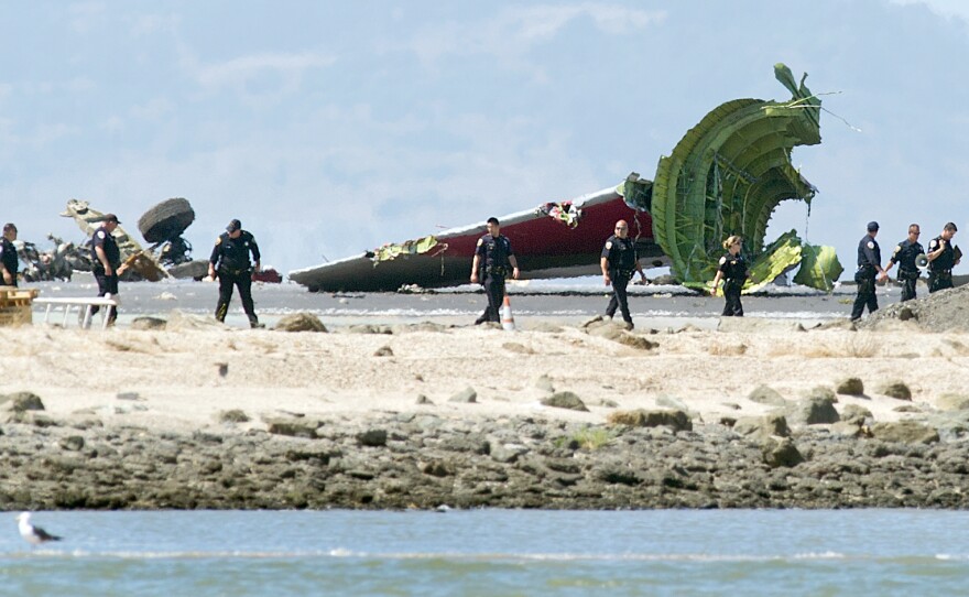 Investigators pass the detached tail and landing gear.