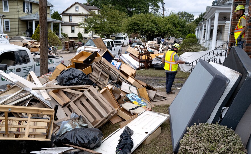 Utility workers work among debris from flood damage caused by the remnants of Hurricane Ida in Manville, N.J., Sunday, Sept. 5, 2021.