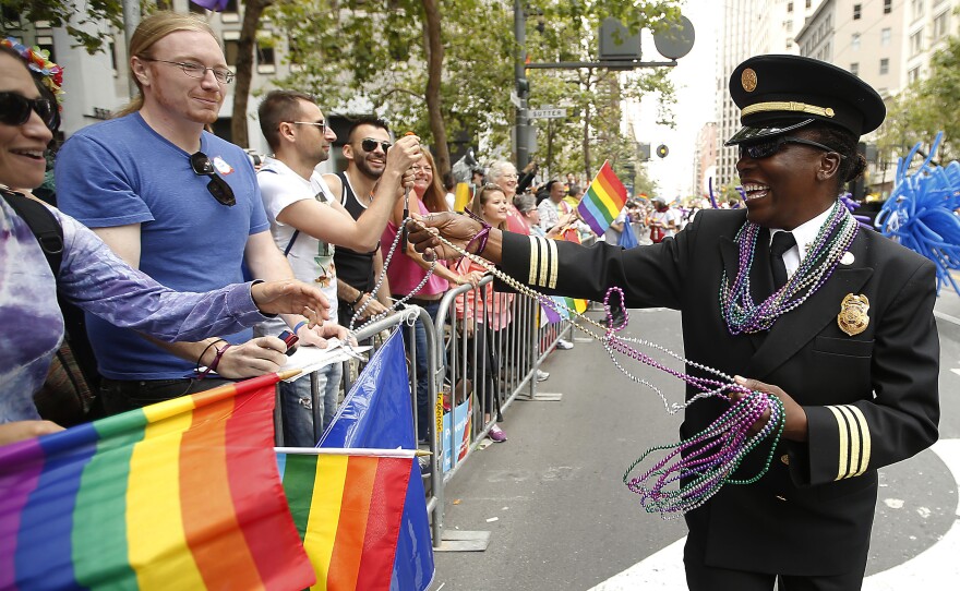 San Francisco Fire Department Deputy Chief Raemona Williams (right) passes out beaded necklaces to the crowd during the 2015 San Francisco Gay Pride Parade.