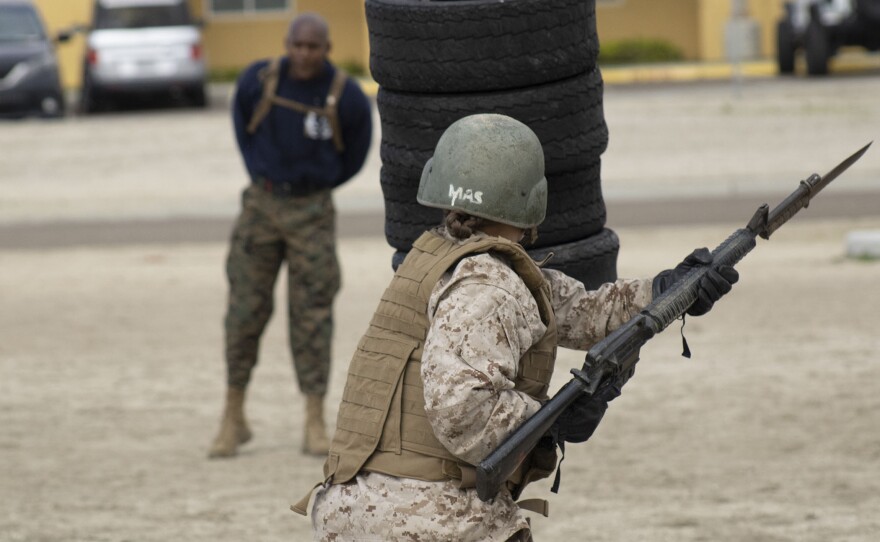 A Marine recruit from Lima Company strikes tires at Marine Corps Recruit Depot, San Diego, as a drill instructor looks on, March 23, 2021.