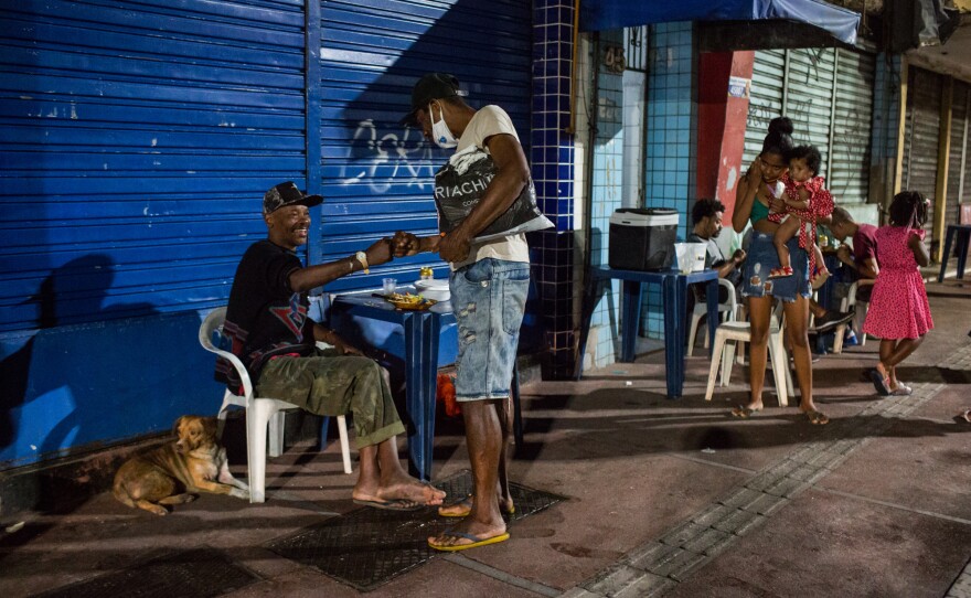 Costa, left, greets his friend Tarciso as he passes by. Since his wife died a few months ago, he has been living on the streets. Without her income, he can no longer afford their apartment.