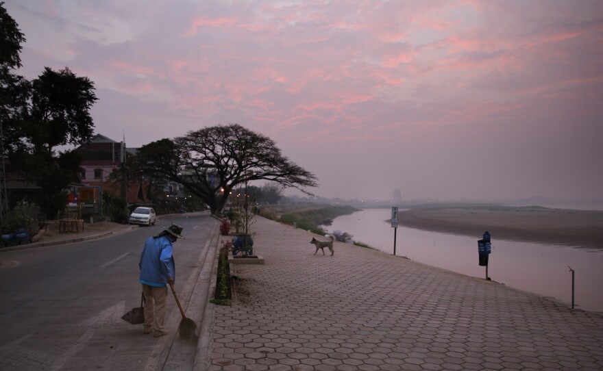 A municipal worker sweeps along a pathway near the Mekong river, in the capital Vientiane, Laos.
